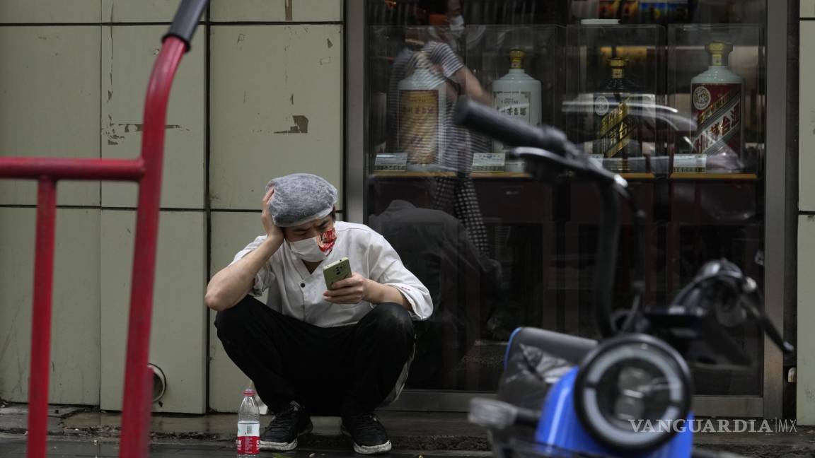 $!El cocinero de un restaurante con una máscara toma un descanso en la acera en Beijing, China