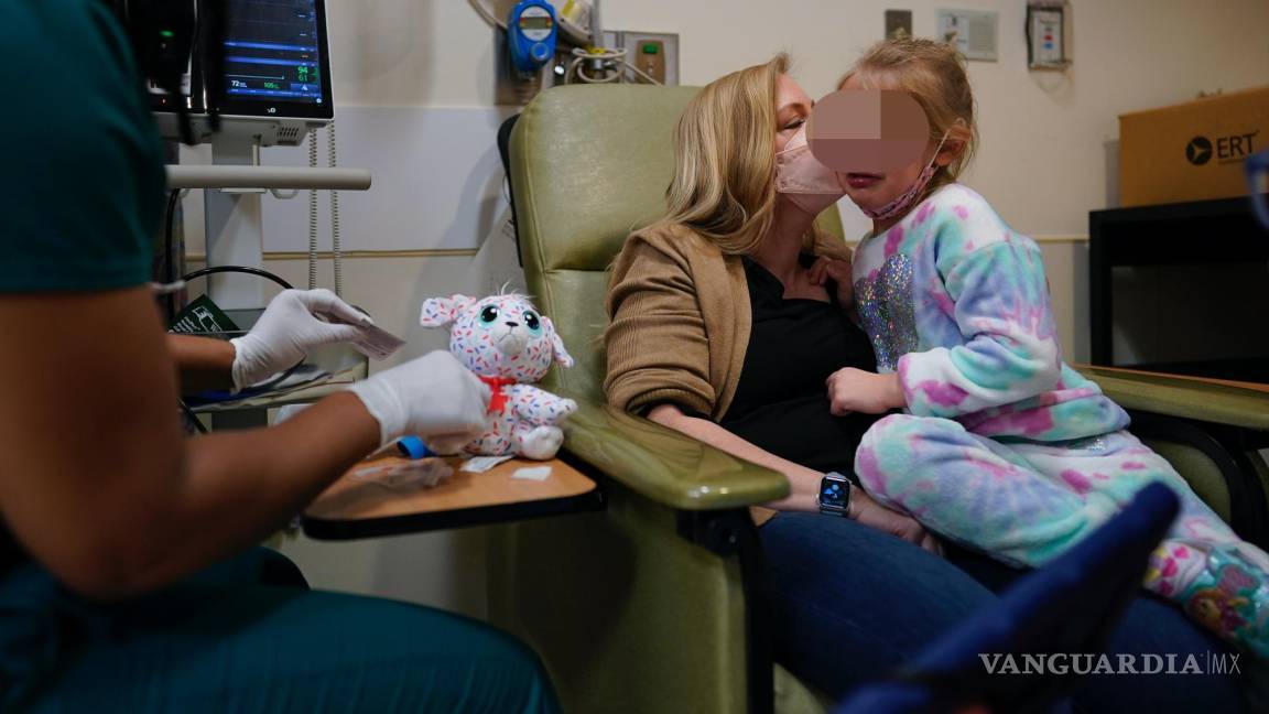 $!Kate Forte besa a su hija Lexie Stroiney, de seis años, mientras la enfermera Michelle Harris usa un peluche para mostrarle cómo le va a sacar sangre.