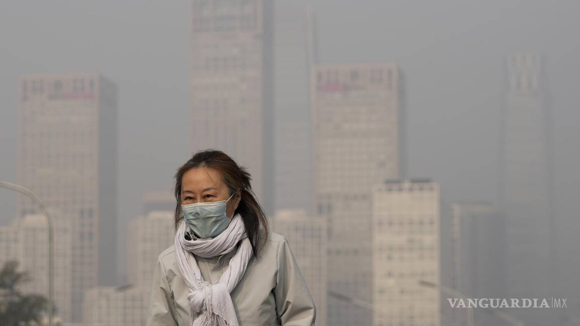 $!Una mujer usa mascarilla contra el COVID-19 camina en medio de la contaminación en Beijing.