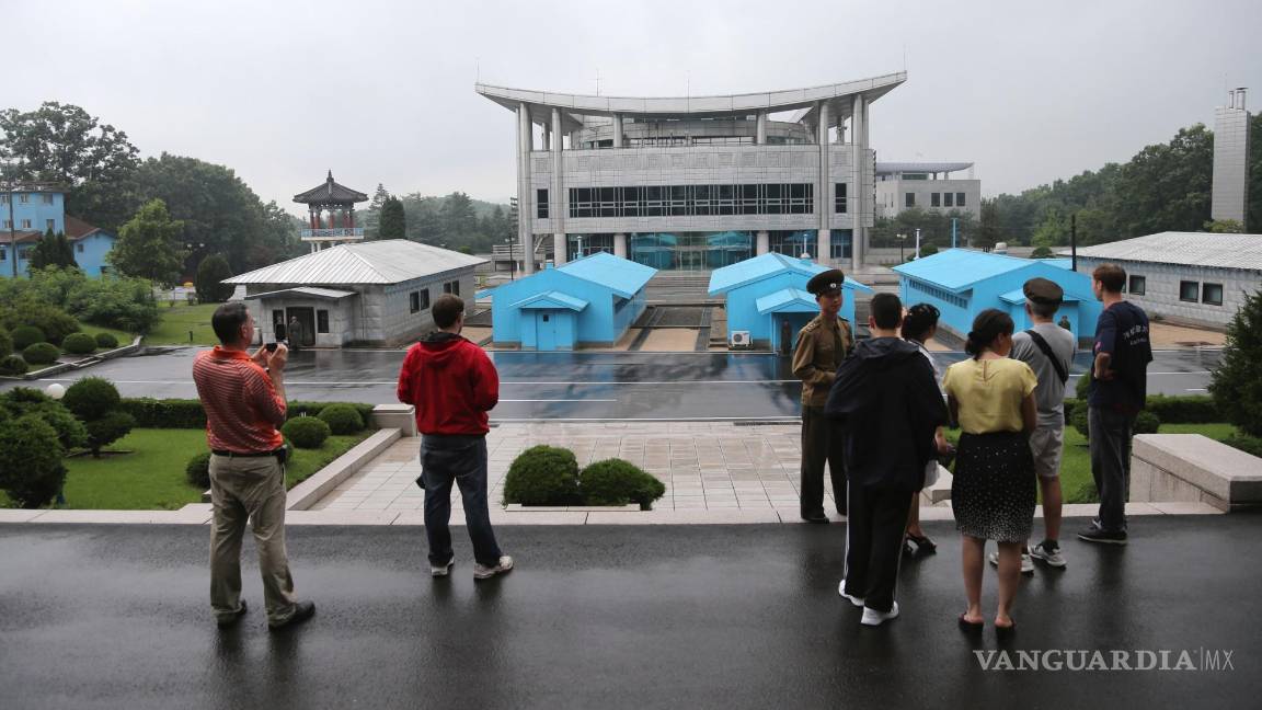 $!Turistas miran hacia un edificio de Corea del Sur mientras los soldados norcoreanos custodian la aldea de Panmunjom en la Zona Desmilitarizada.