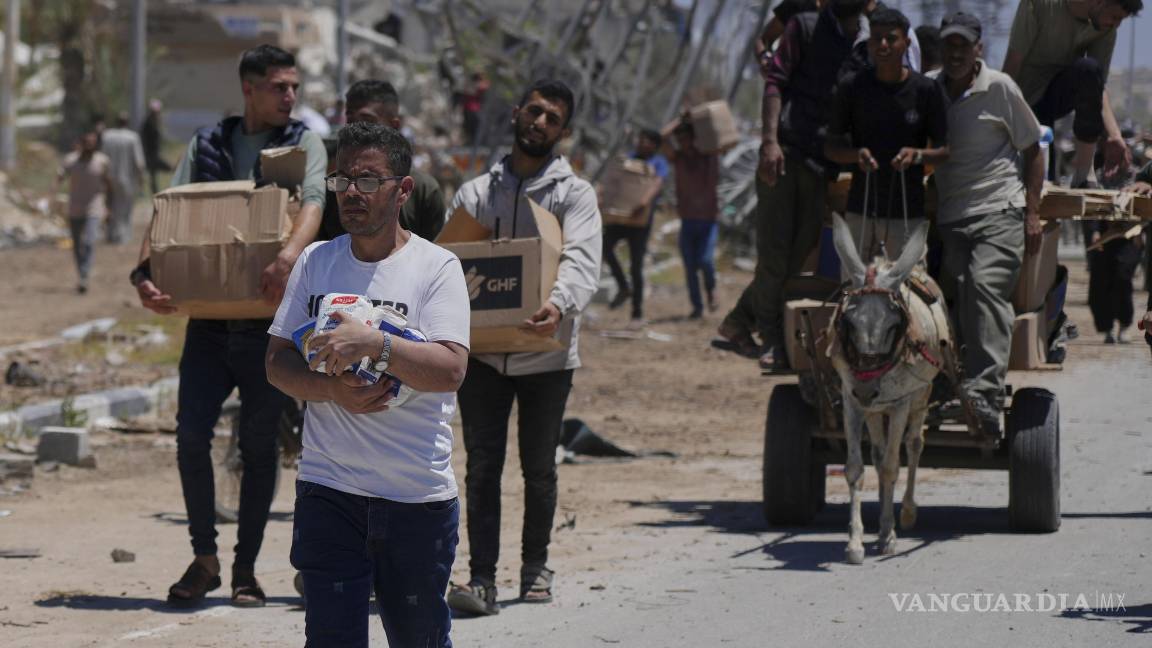 $!Palestinos cargan ayuda humanitaria entregados por la Fundación Humanitaria de Gaza, una organización respaldada por Estados Unidos y aprobada por Israel.