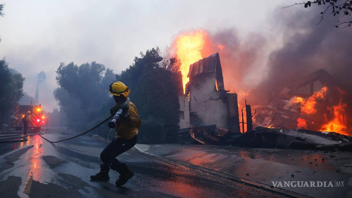 $!Un bombero intenta contener el avance de un incendio que consume una estructura en Pacific Palisades, el martes 7 de enero de 2025, en Los Ángeles.
