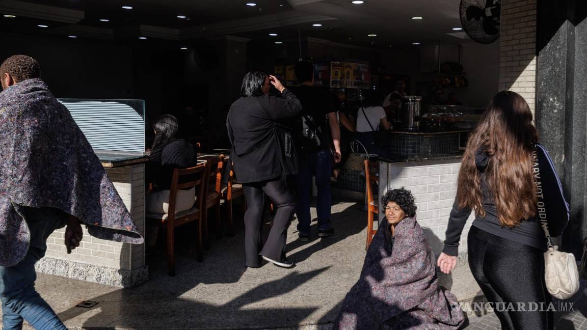 $!Una persona en situación de calle descansa frente a un restaurante en el centro de la ciudad, en Sao Paulo, Brasil.