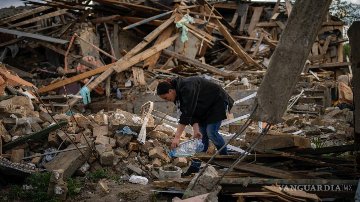 $!Anna Shevchenko riega las pocas flores que sobrevivieron a los proyectiles caídos en su jardín, cerca de Kiev, Ucrania, el martes 3 de mayo de 2022.