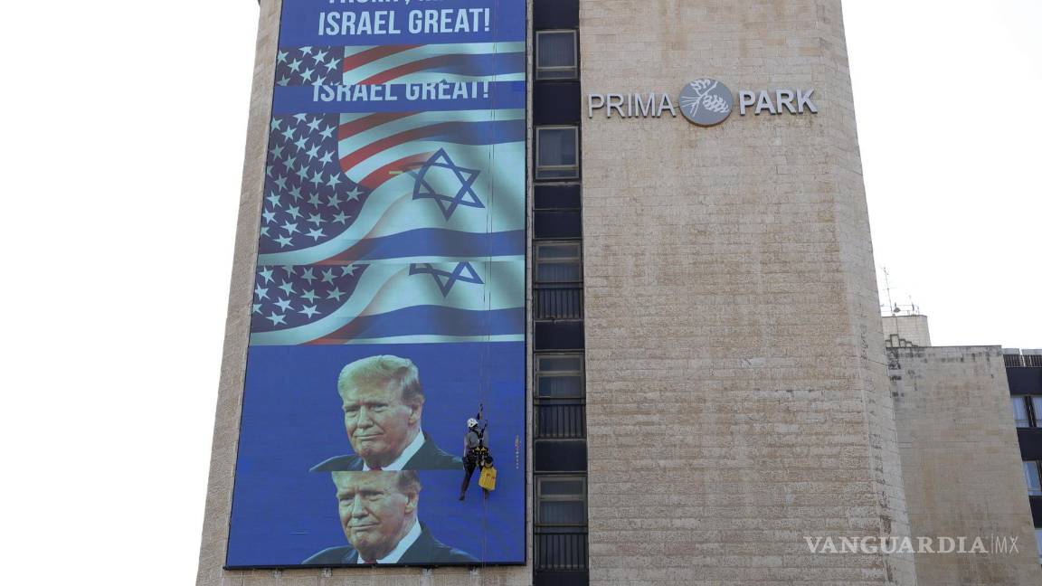$!Un trabajador colgado en un edificio en el que se exhibe un gran cartel de felicitación a Donald Trump, a la entrada de Jerusalén.