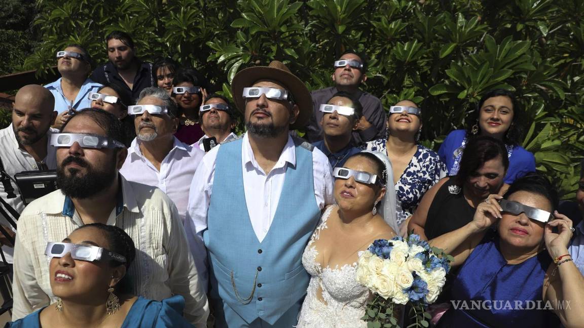 $!Los novios Isaac Medina (centro) y Jazmin González observan un inusual eclipse solar antes de la ceremonia de su boda, en Mérida, México, el 14 de octubre de 2023.