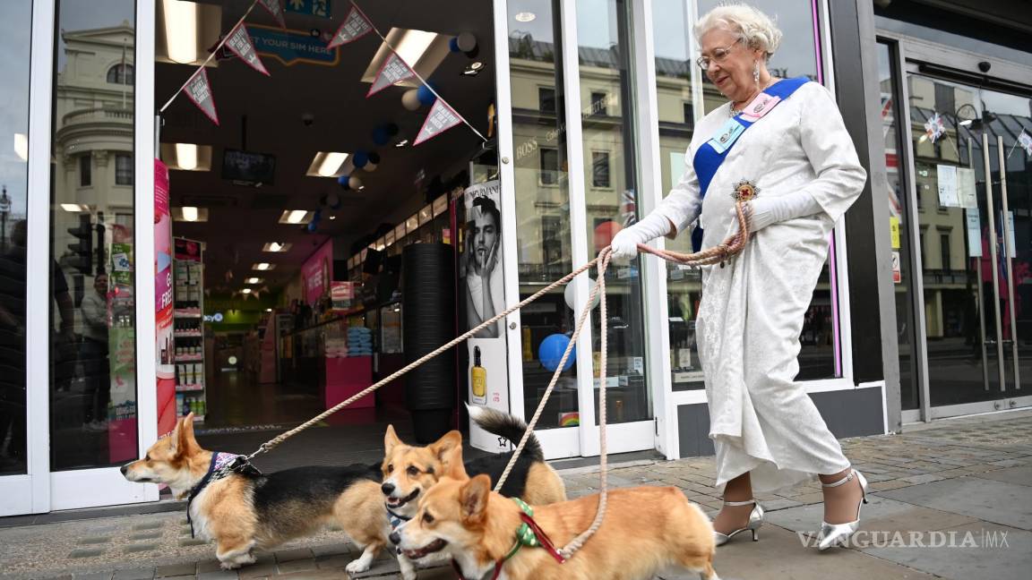 $!Una mujer disfraza de la reina Isabel II pasea a sus perros por una calle de Londres.