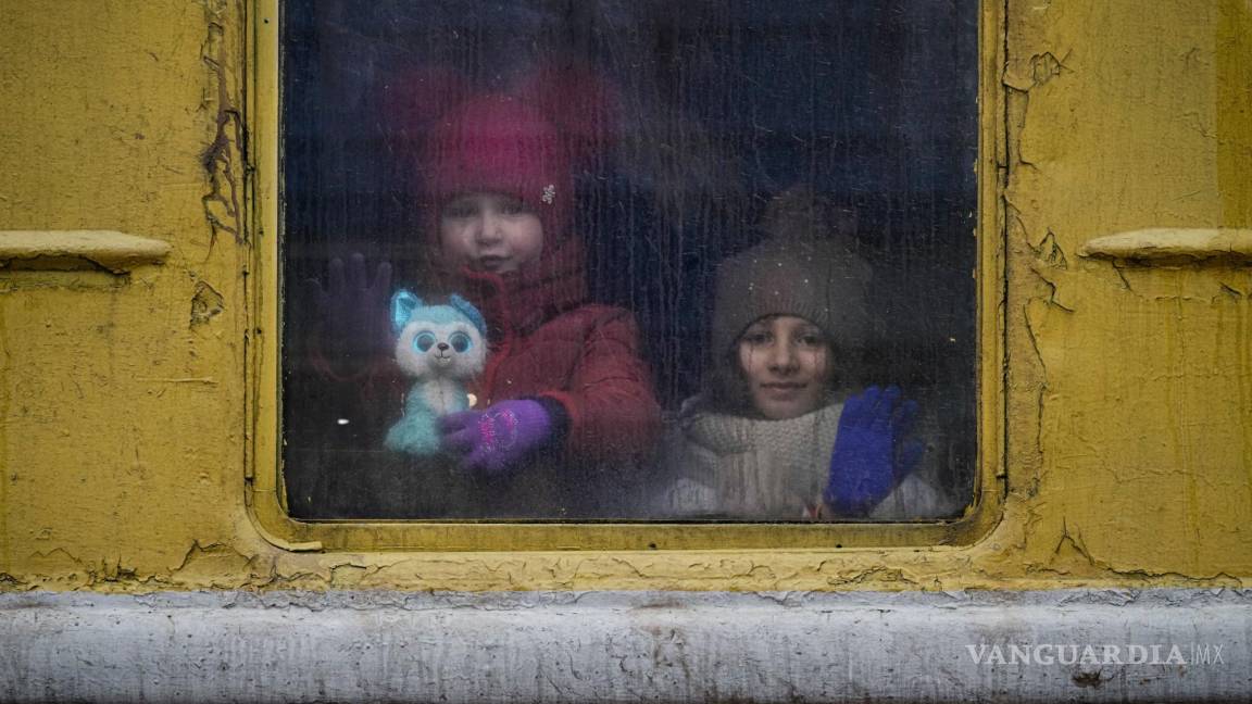 $!Niños mirando por la ventana de un tren sin calefacción con destino a Leópolis, en Kiev, Ucrania, el jueves 3 de mazo de 2022.