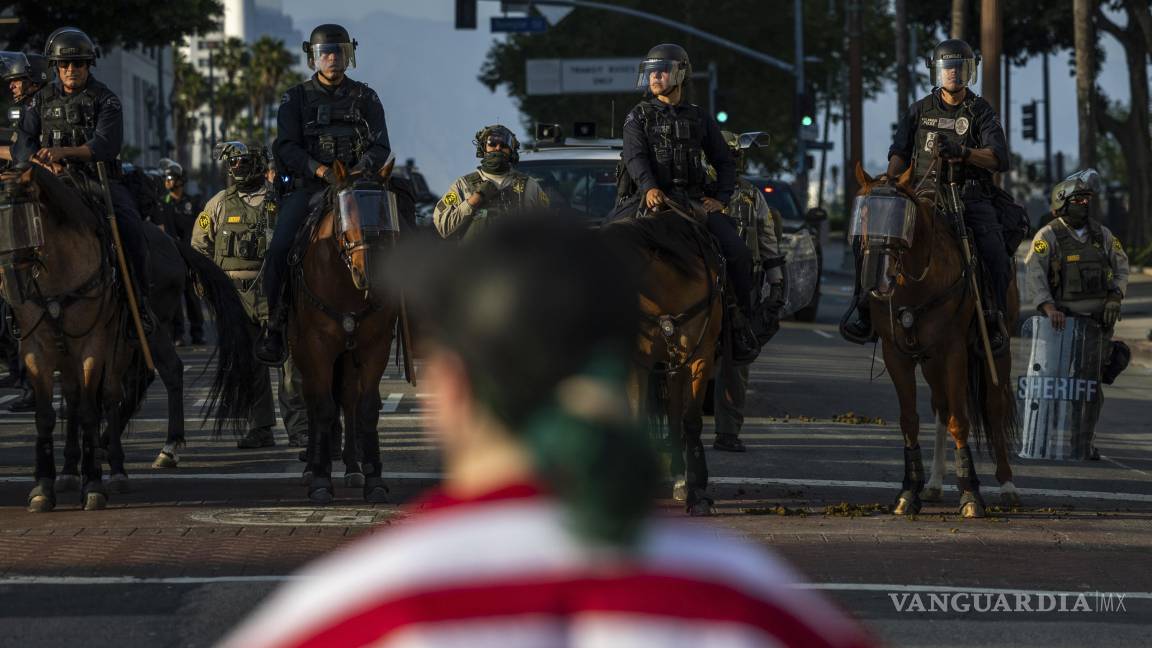 $!Agentes de policía, frente a manifestantes en el exterior del edificio del ayuntamiento durante protestas contra las redadas migratorias federales en Los Ángeles.