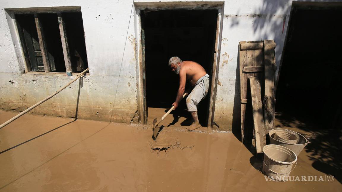 $!Hombre sacando el lodo y agua de su hogar.