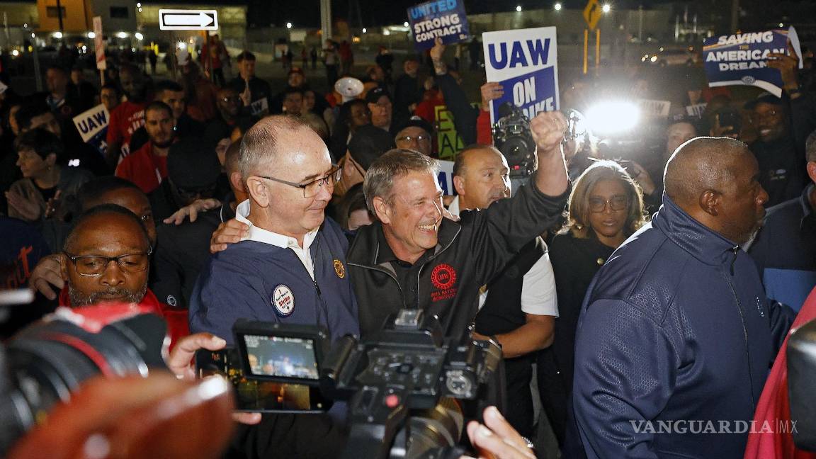 $!El presidente del sindicato UAW, Shawn Fain (i), celebra junto al vicepresidente, Chuck Browning (c), frente a la fábrica Ford Michigan Assembly en Wayne.