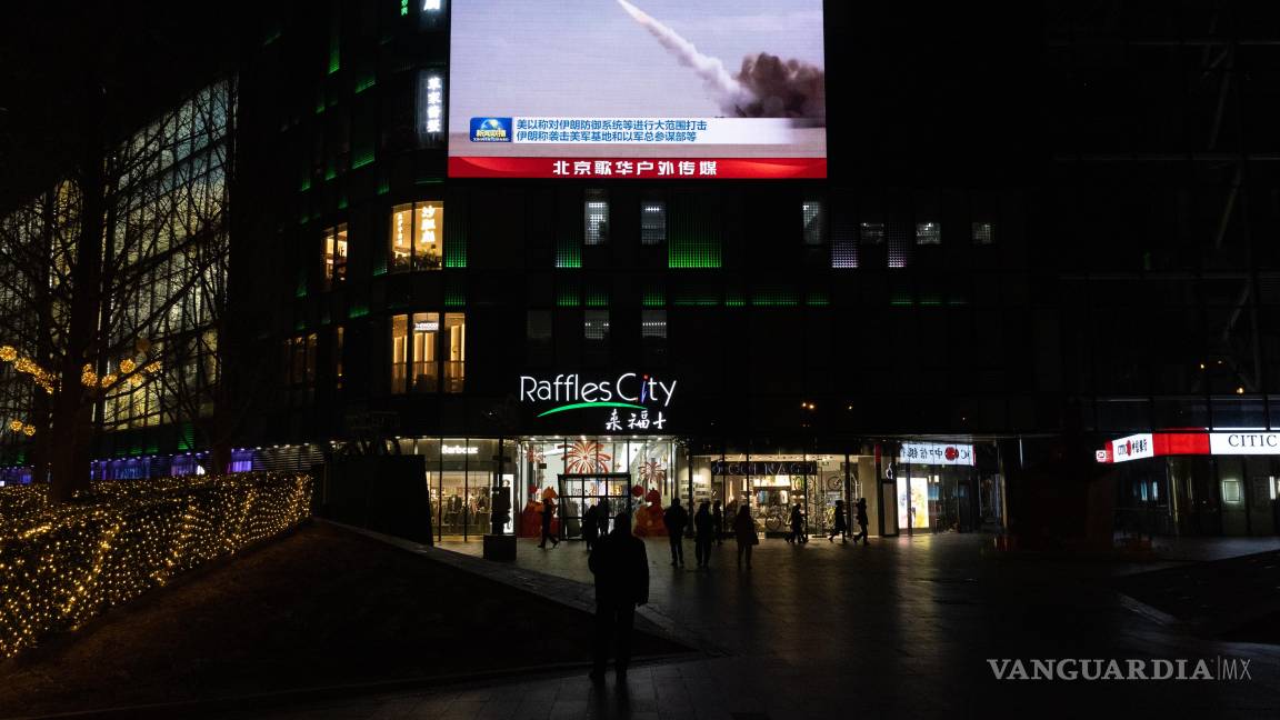 $!Personas observan una transmisión en una pantalla en un centro comercial sobre los ataques estadounidenses e israelíes en Irán y el contraataque iraní, en Pekín.