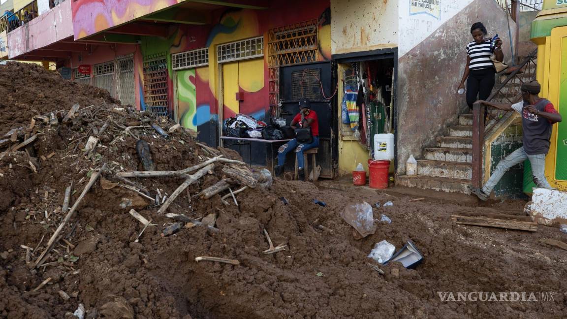 $!Personas caminan por el lodo en una calle afectada por el paso del huracán Melissa en Santa Cruz, Jamaica.