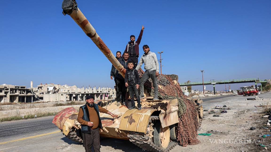 $!Un grupo de sirios se encuentran en la parte trasera de un tanque en la Autopista Internacional Alepo-Damasco M5, capturada por la oposición siria, Siria.