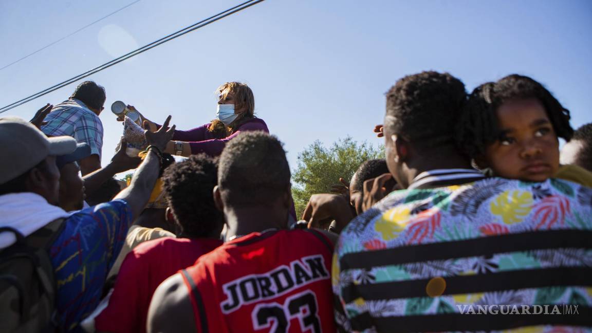 $!Araselli Zamora from San Antonio hands resources including food, clothing and baby carriers to a group of migrants early Friday, Sept. 17, 2021, in Ciudad Acuña, Mexico. Haitians crossed the Rio Grande freely and in a steady stream, going back and forth between the U.S. and Mexico through knee-deep water with some parents carrying small children on their shoulders. Unable to buy supplies in the U.S., they returned briefly to Mexico for food and cardboard to settle, temporarily at least, under or near the bridge in Del Rio, a city of 35,000 that has been severely strained by migrant flows in recent months. (Marie D. De Jesús/Houston Chronicle via AP)