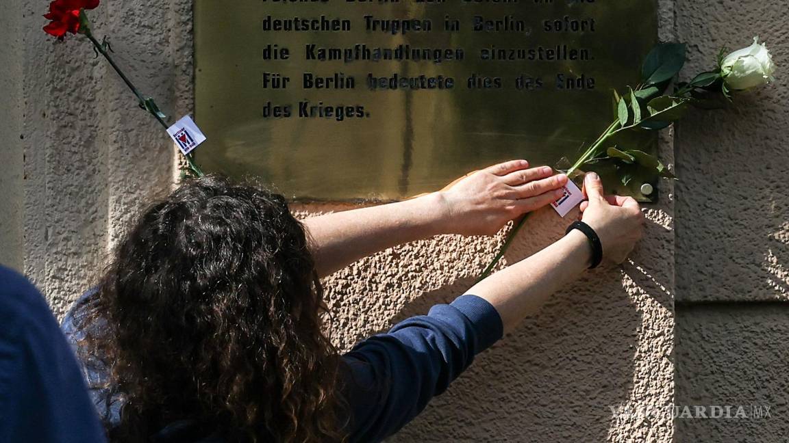 $!Una mujer coloca una flor en la fachada de una casa en el sitio histórico de la Capitulación de Berlín, en la calle Schulenburgring en Berlín, Alemania.