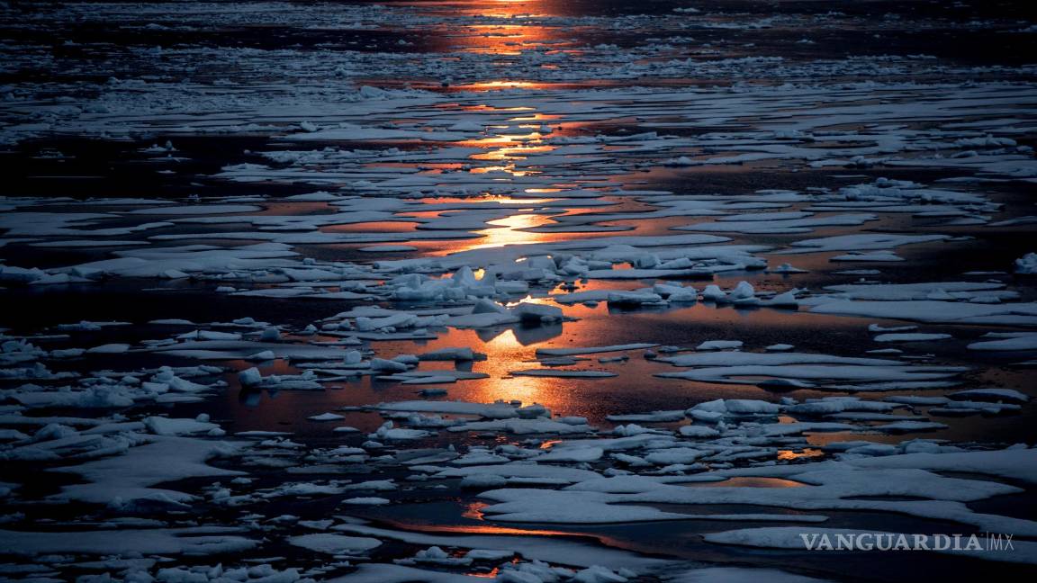 $!El sol de medianoche brilla a través del hielo marino a lo largo del Pasaje del Noroeste en el archipiélago ártico canadiense, el domingo 23 de julio de 2017. Cuando está cubierto de nieve y hielo, el Ártico refleja la luz solar y el calor. Pero esa manta está menguando. Y a medida que se derrite más hielo marino en el verano, “estás revelando superficies oceánicas realmente oscuras, como una camiseta negra”, dice la científica del hielo Twila Moon. Como la ropa oscura, los parches abiertos del mar absorben el calor del sol más fácilmente. AP/David Goldman