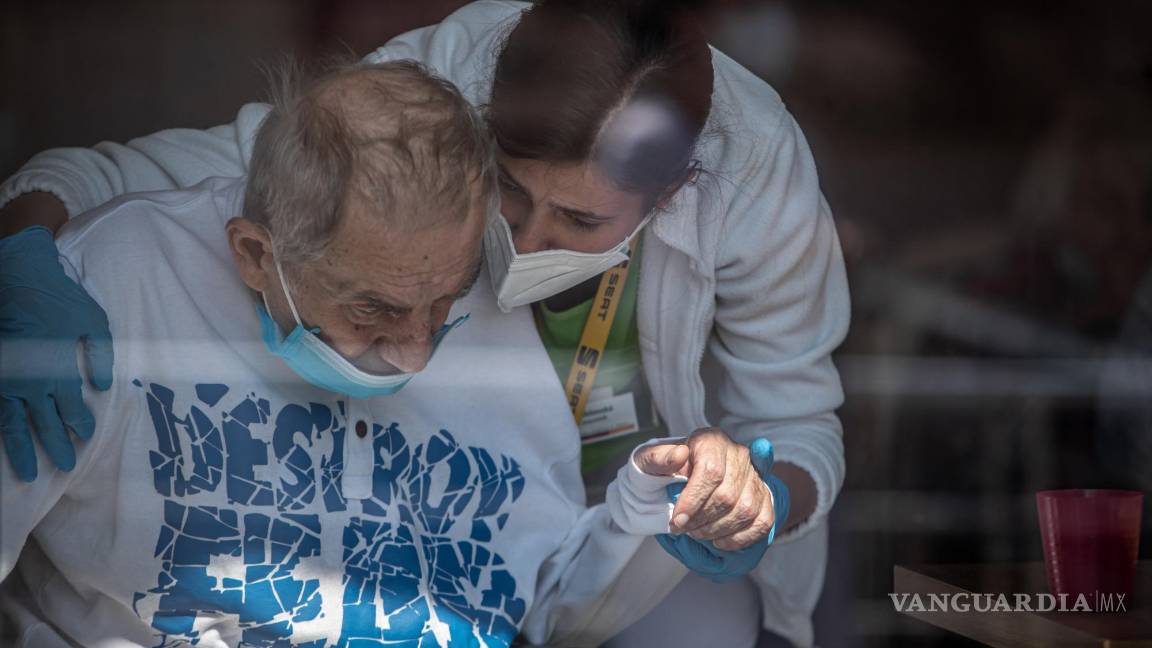 $!Un sanitario con mascarilla sostiene la mano de un residente de una casa de Alzheimer en Pitkovice, República Checa. EFE/EPA/Martin Divisek