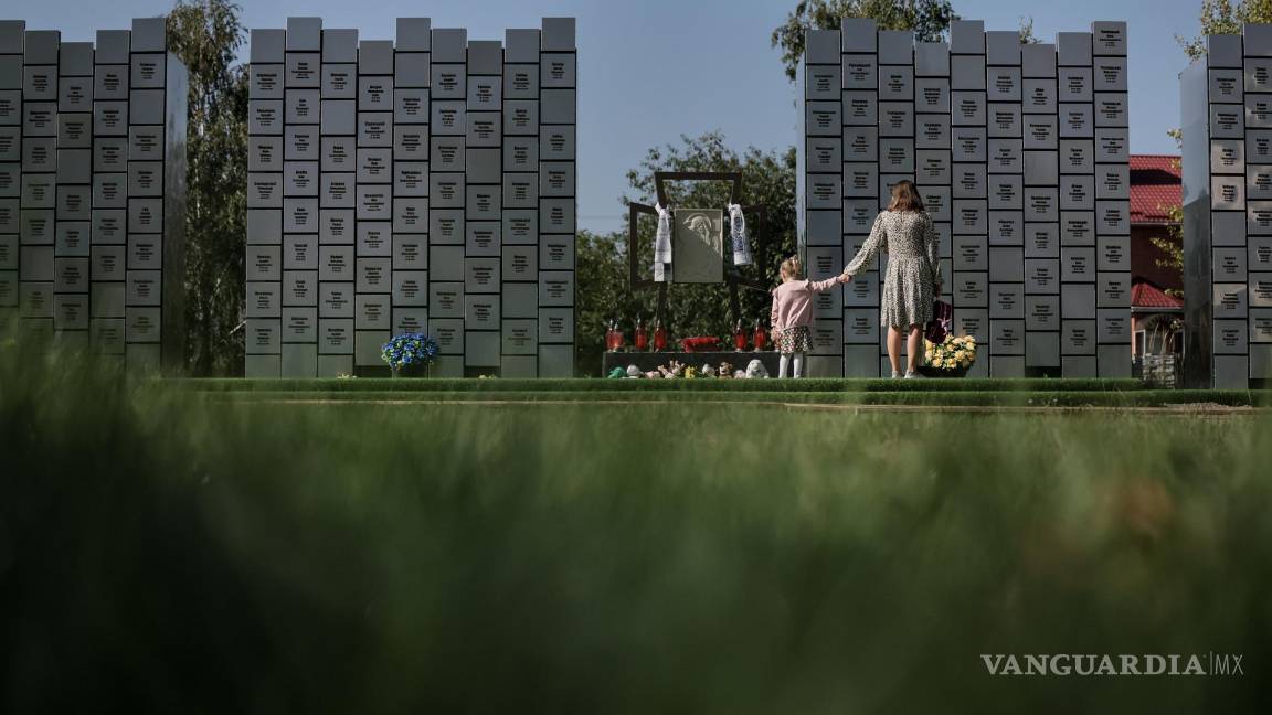 $!Una mamá con su hija visitan un monumento conmemorativo con los nombres de 501 personas identificadas víctimas de crímenes de guerra, en Bucha, Ucrania.