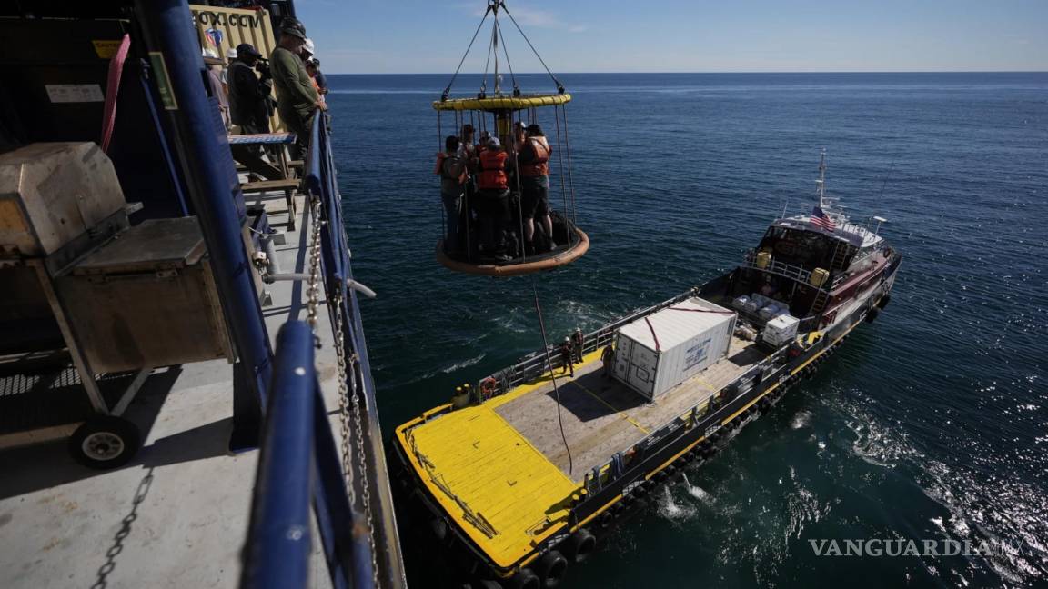 $!Los miembros de la Expedición 501 en una canasta Billy Pugh son bajados de la plataforma del barco elevador Robert al Gaspee.