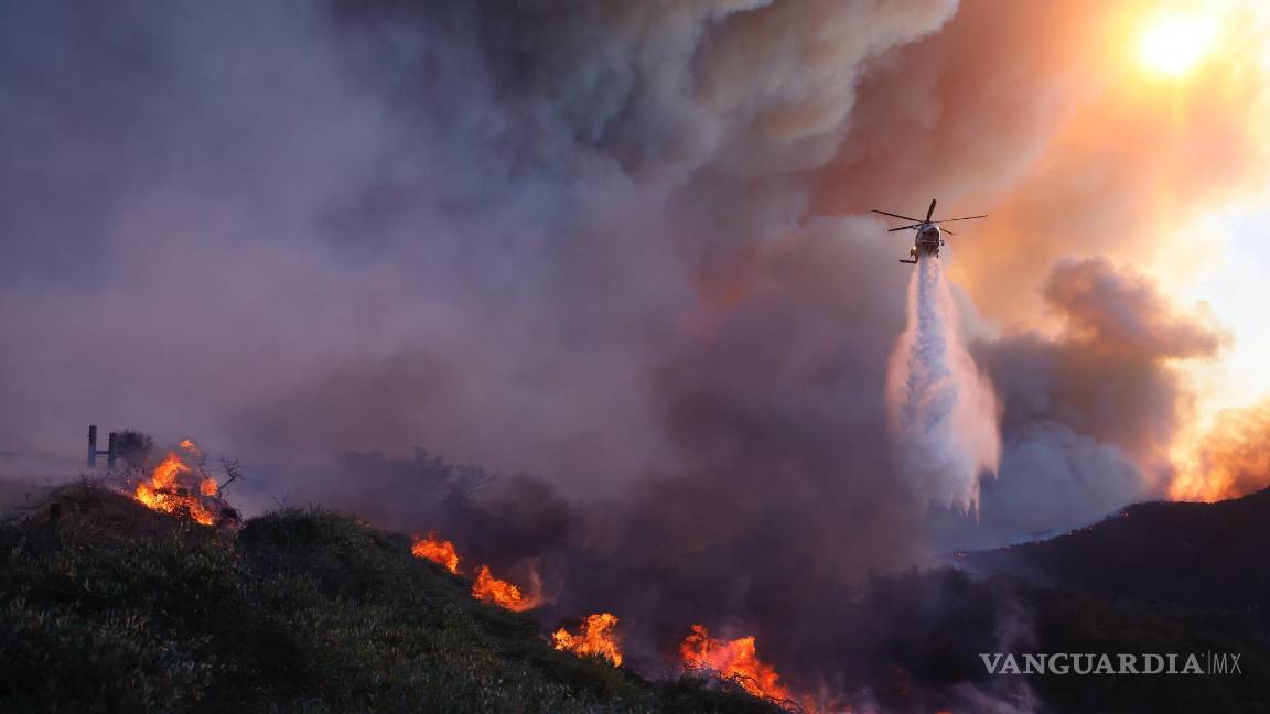 $!Un helicóptero arroja agua sobre el incendio Palisades que avanza en el vecindario Pacific Palisades de Los Ángeles, el martes 7 de enero de 2025.