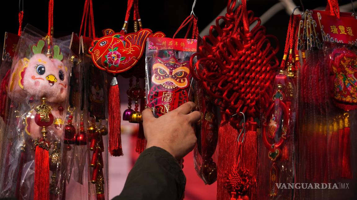 $!Un hombre elige un ornamento para atraer la prosperidad en un puesto de un mercado en la víspera del Año Nuevo Lunar, en Beijing.