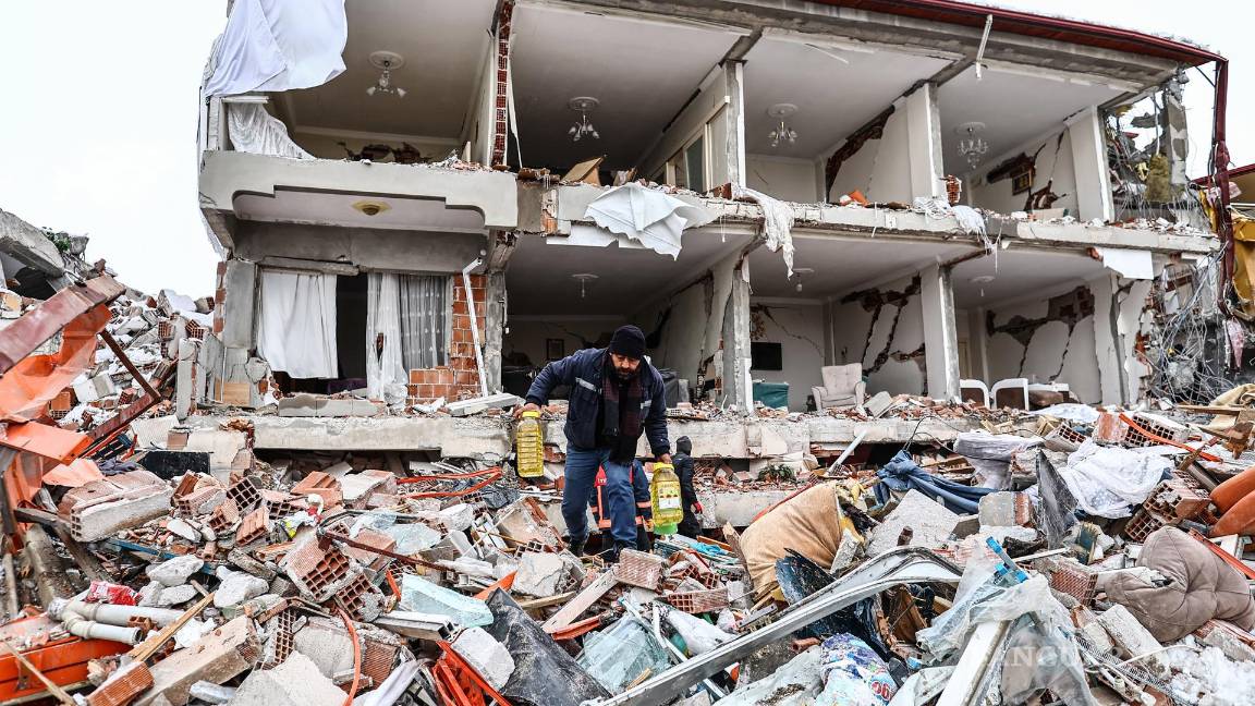 $!Las personas llevan alimentos rescatados de un edificio derrumbado después de un poderoso terremoto en el distrito de Elbistan de Kahramanmaras, Turquía.