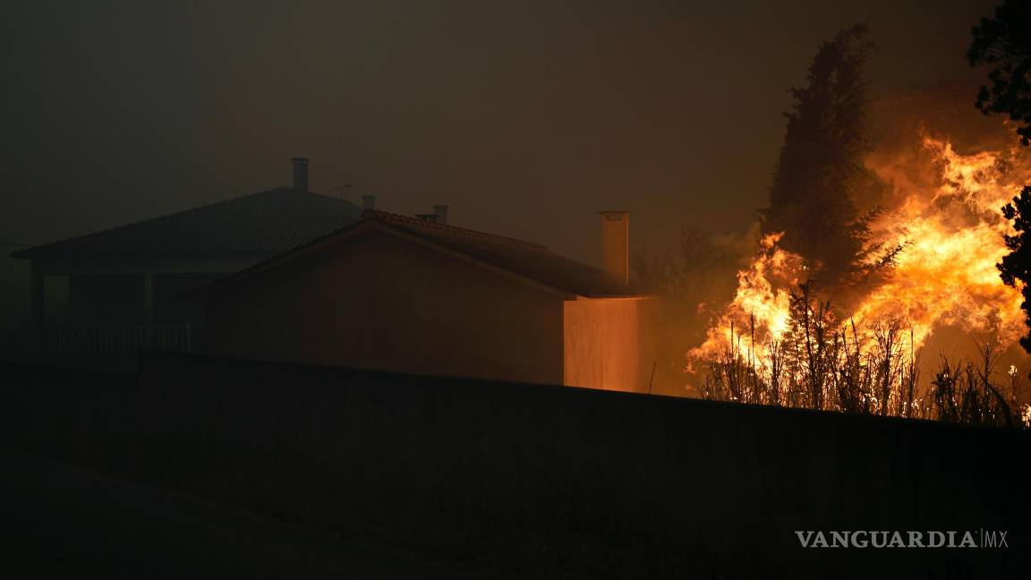 $!Un incendio forestal llega a una casa vacía mientras el humo oscurece el cielo en el pueblo de Bemposta, cerca de Ansiao, en el centro de Portugal.