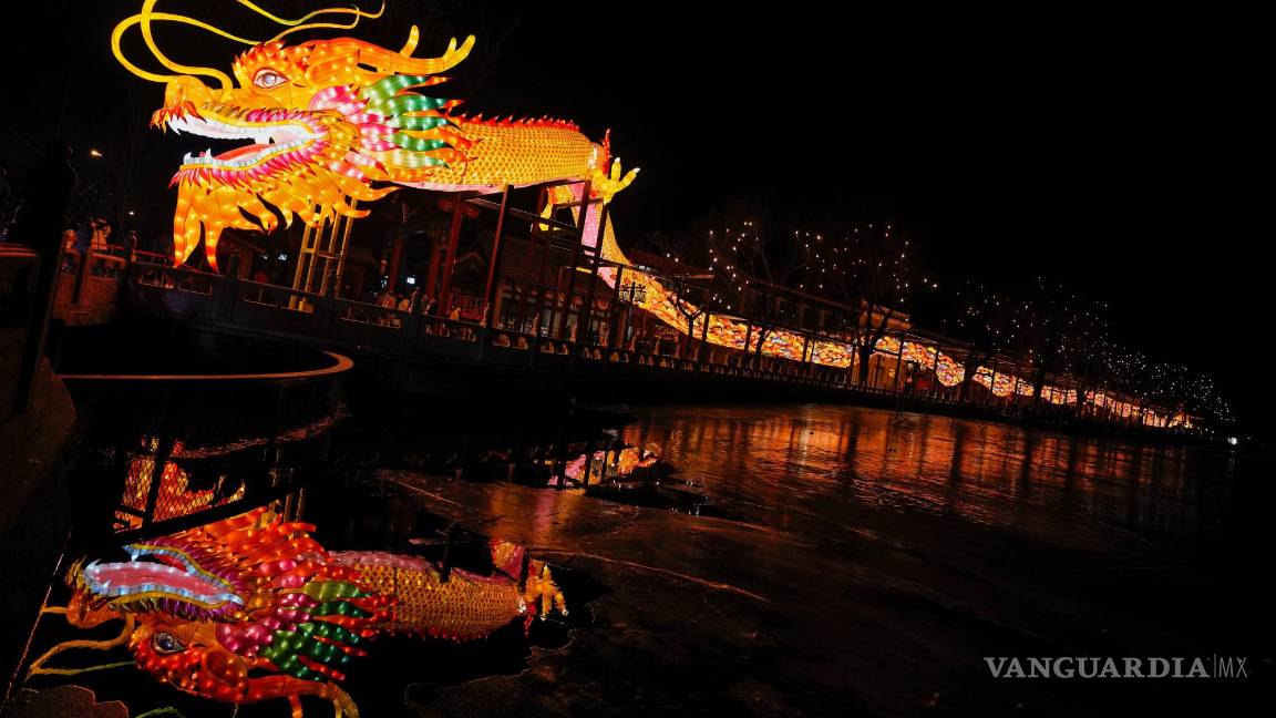 $!Visitantes pasan por debajo de una linterna enorme con forma de dragón, en el lago Houhai, en Beijing.