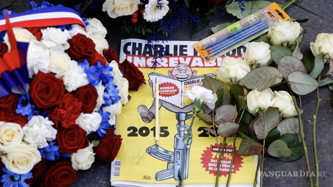 $!Una edición especial del periódico satírico francés Charlie Hebdo entre coronas de flores y lápices dejados frente a las antiguas oficinas de Charlie Hebdo.
