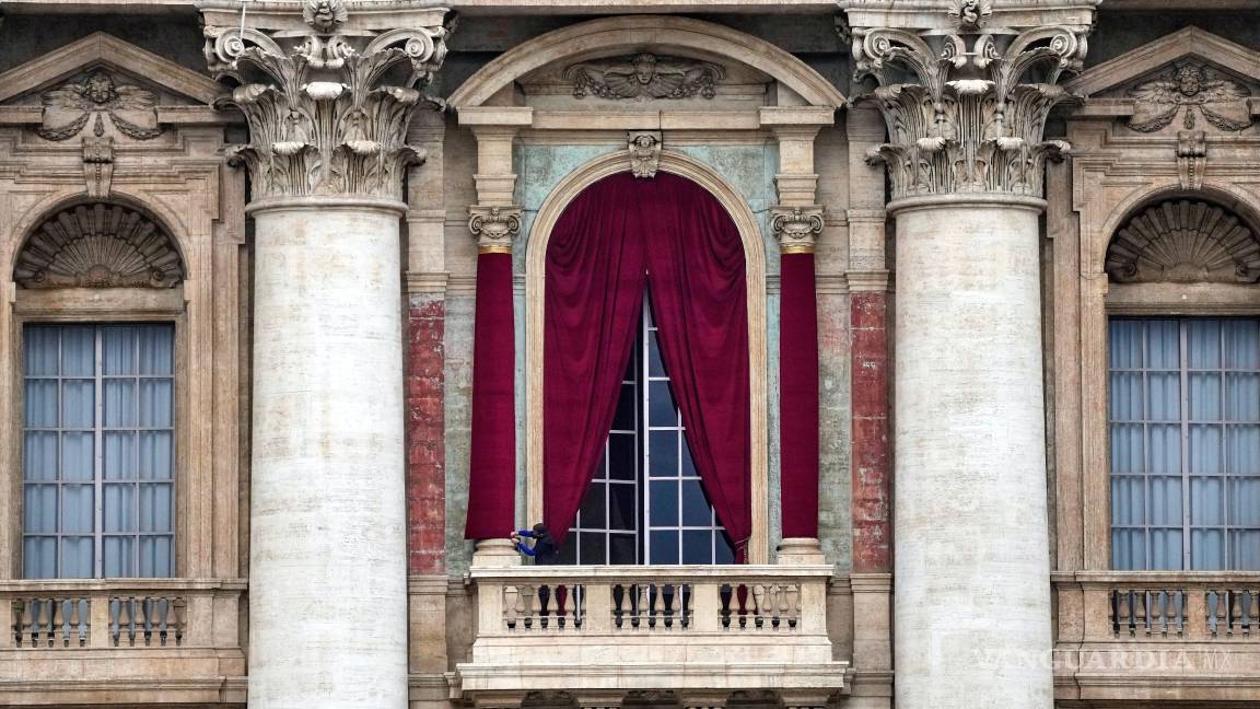 $!Un hombre da el último toque a un paño rojo que envuelve una columna de la logia central de la Basílica de San Pedro en donde el nuevo papa dará un discurso.