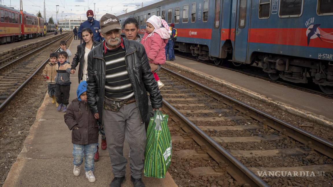 $!Refugiados que huyen de la guerra en la vecina Ucrania caminan sobre un andén en Zahony, Hungría. AP/Balazs Kaufmann