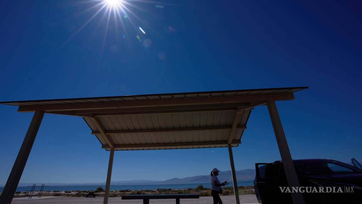 $!Una mujer recoge sus pertenencias tras descansar en una zona bajo la sombra junto al mar de Salton.