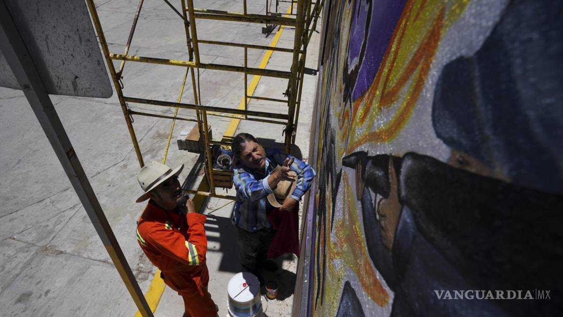 $!El artista mexicano Jesús Rodríguez(d) instruye a Luis Manuel Vélez frente a un mural que Rodríguez está pintando en la fachada de un auditorio en San Salvador.