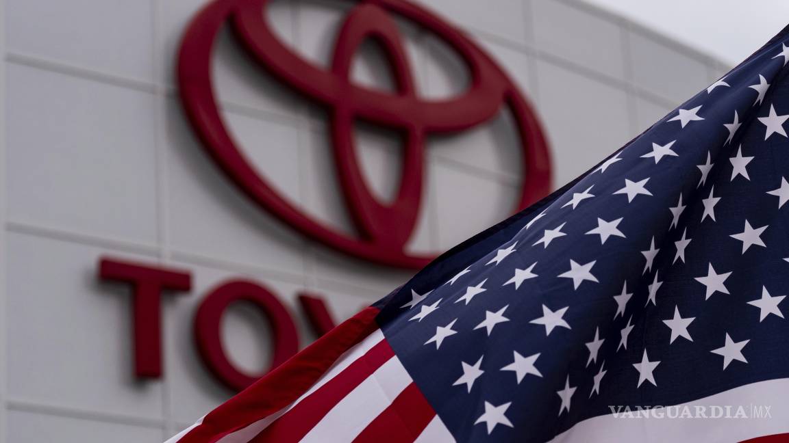 $!Una bandera estadounidense ondea al viento frente al logotipo de Toyota en un concesionario de Cerritos, California.