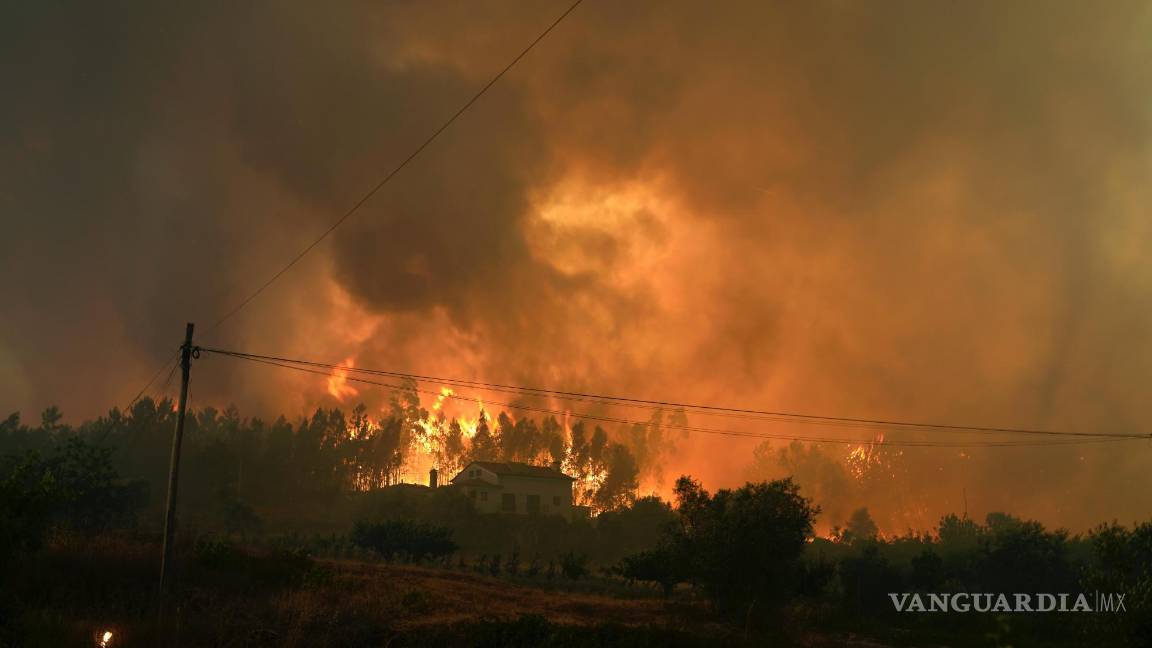 $!Un incendio forestal se cierra en una casa en el pueblo de Bemposta, cerca de Ansiao, en el centro de Portugal.