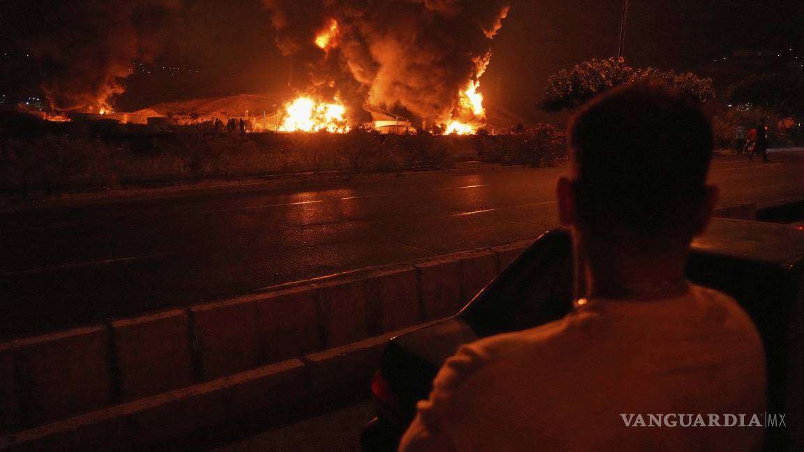 $!A man looks at flames rising from an oil storage facility after it appeared to have been struck by an Israeli strike in Tehran, Iran, early Sunday, June 15, 2025. (AP Photo/Vahid Salemi)