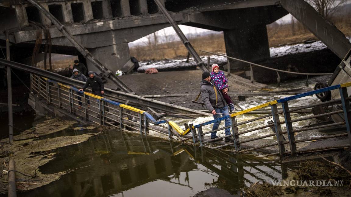 $!La combatiente Valery, de 37 años, carga a un niño mientras ayuda a una familia a cruzar un puente que fue destruido por artillería, el miércoles 2 de marzo de 2022, en Kiev. (AP Foto/Emilio Morenatti)