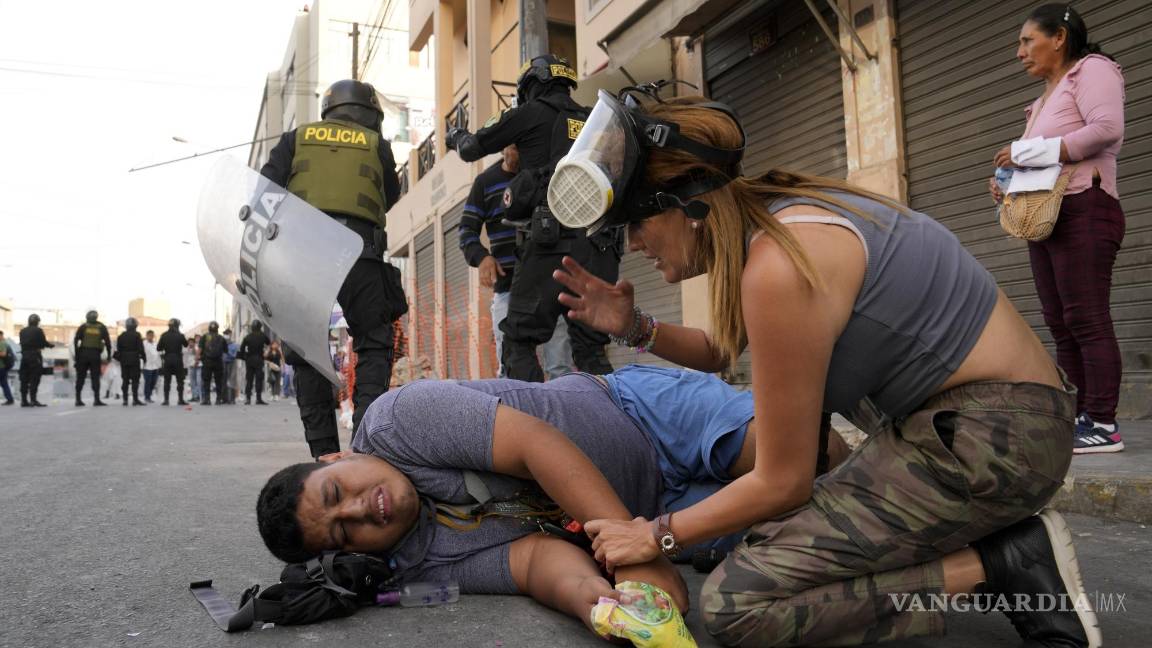 $!Una mujer atiende a un manifestante de oposición que cayó al suelo durante una marcha contra la presidenta peruana Dina Boluarte en Lima, Perú.