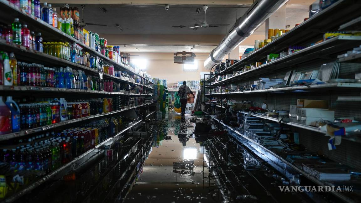 $!Con el permiso del dueño del supermercado, un residente se sirve provisiones y alimentos en Black River, Jamaica tras el paso del huracán Melissa.