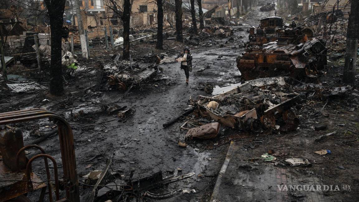 $!Una mujer pasa por una calle llena de restos de vehículos militares destruidos en Bucha, a las afueras de Kiev, Ucrania, el domingo 3 de abril de 2022.