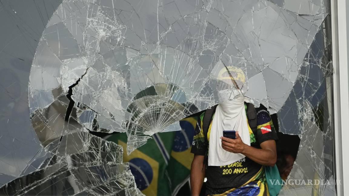 $!Los manifestantes, simpatizantes del expresidente de Brasil, Jair Bolsonaro, hacen pucheros desde una ventana rota después de asaltar el Palacio Planalto en Brasilia.