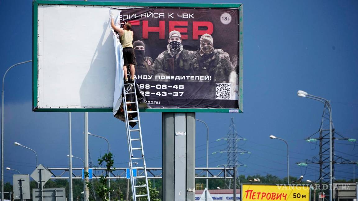 $!Un hombre quita el cartel que dice “Únase a nosotros en Wagner” sobre una carretera en las afueras de San Petersburgo, Rusia.