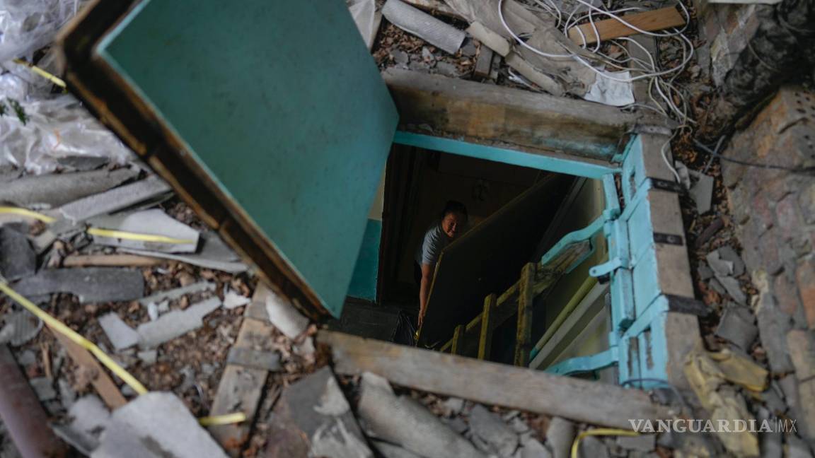 $!Liudmyla Voronina se ve a través de la trampilla de su tejado mientras está de pie en su casa, dañada por los ataques en Irpin, Ucrania, el jueves 26 de mayo de 2022.