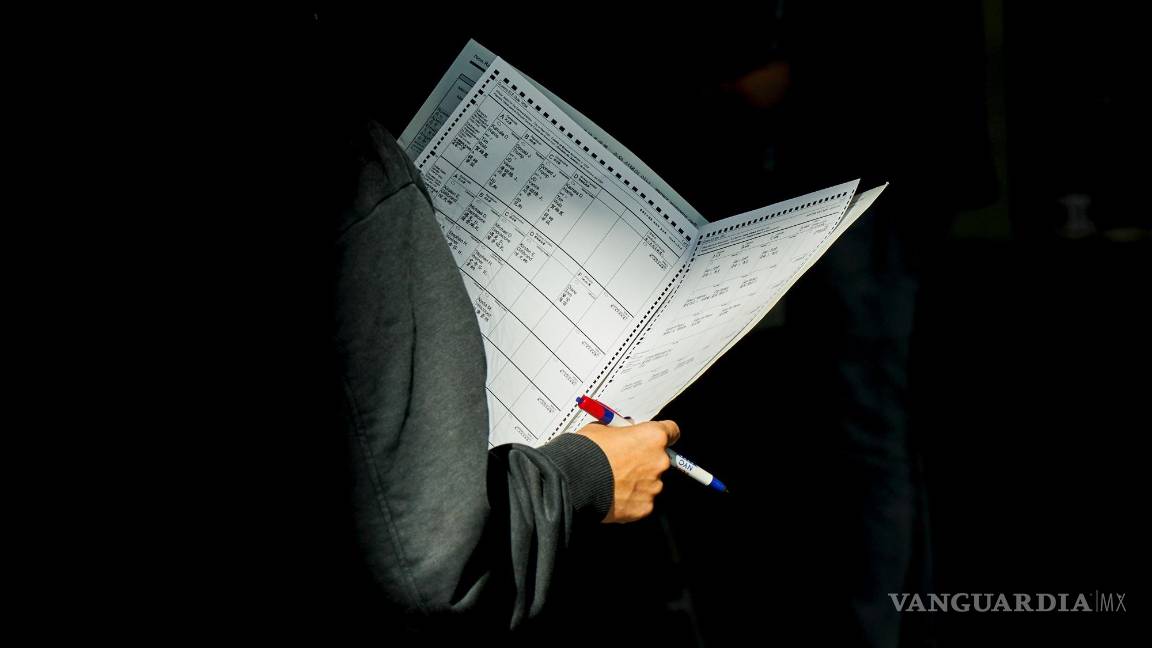 $!Una mujer mira su papeleta mientras hace cola para la votación anticipada en un centro de votación en Queens.
