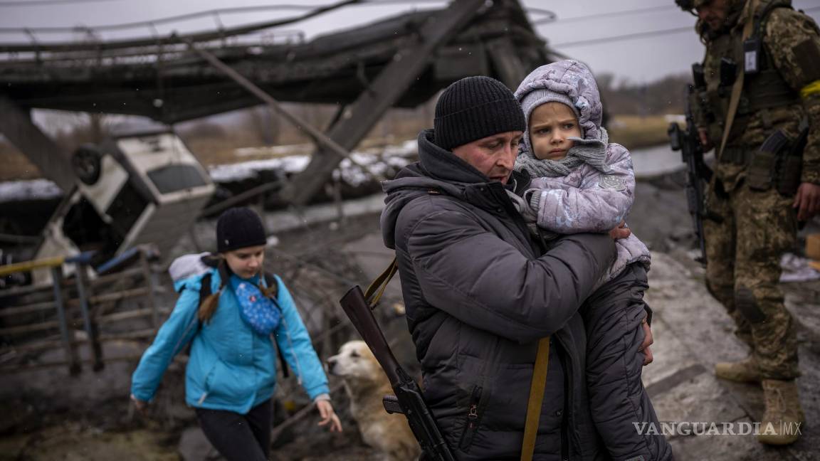 $!El miliciano local Valery, de 37 años, ayuda a una familia que huye junto a un puente destruido por fuego de artillería a las afueras de Kiev. AP/Emilio Morenatti