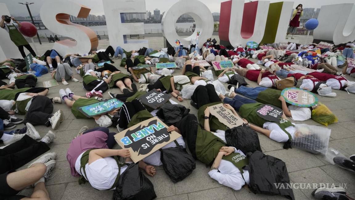 $!Activistas con bolsas de plástico se acuestan en el suelo durante una campaña para conmemorar el Día de la Tierra contra el cambio climático en Seúl.