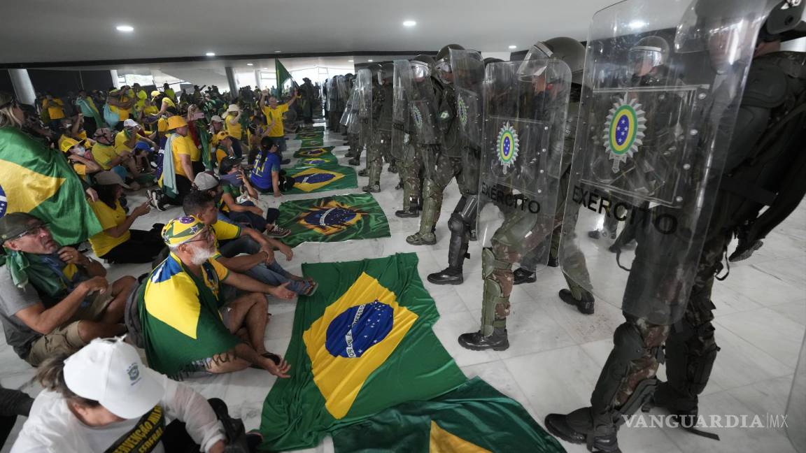 $!Simpatizantes del expresidente de Brasil, Jair Bolsonaro, se sientan frente a la policía después de entrar al Palacio de Planalto después de asaltarlo, en Brasilia.