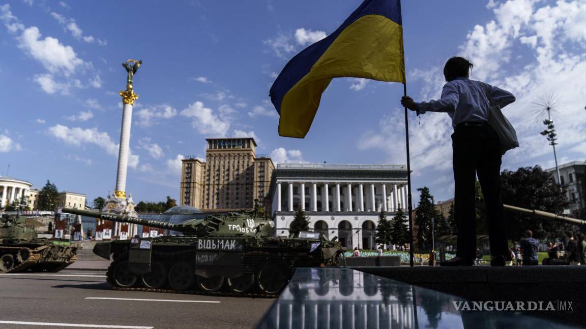 $!Una mujer sostiene la bandera de Ucrania mientras observa una fila de vehículos militares rusos destruidos en exhibición en la plaza Maidan en Kyiv, Ucrania.