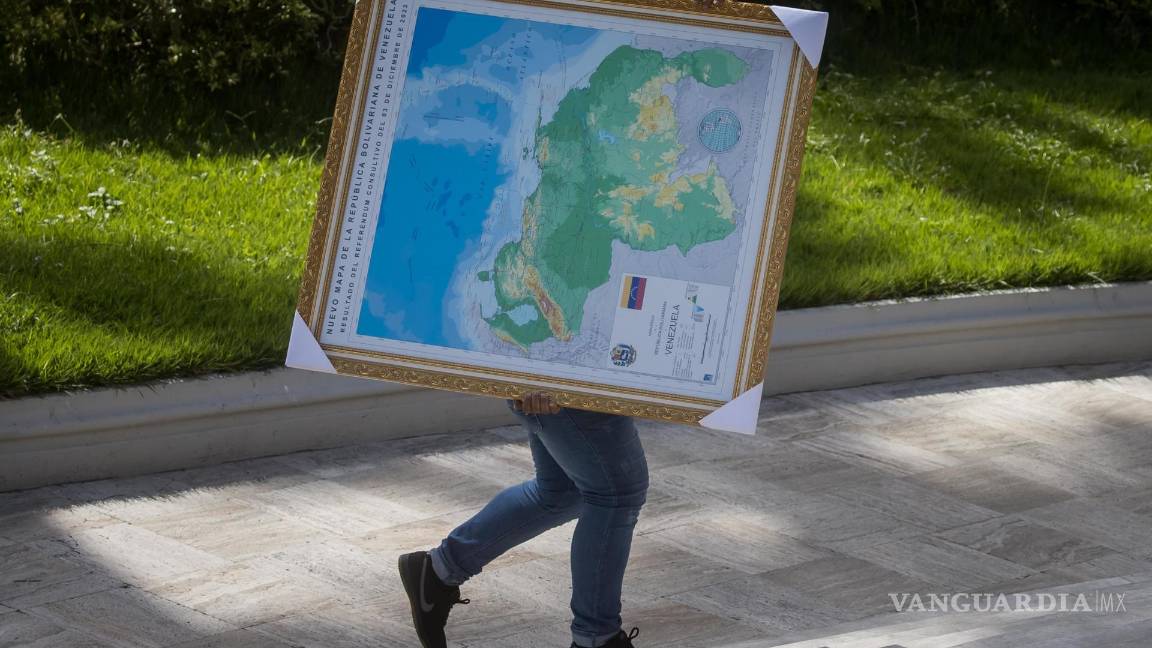 $!Un hombre carga un cuadro del mapa de Venezuela con la adhesión del Esequibo, en uno de los jardines del Palacio Federal Legislativo en Caracas, Venezuela.